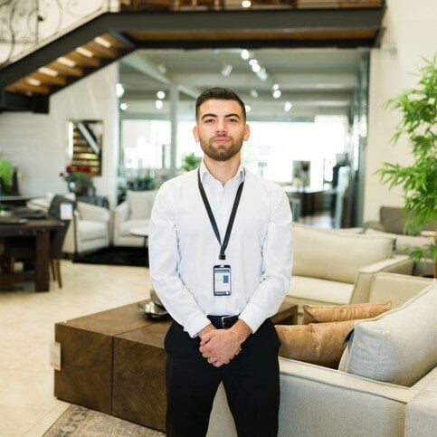 Furniture store owner standing proudly in their showroom with a selection of home furnishings.