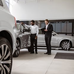 Customer and dealership salesperson discussing car features while browsing the showroom