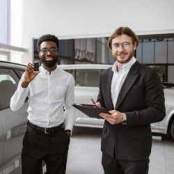 Happy customer receiving car keys from a dealership owner after using CrossCheck’s flexible payment solutions.
