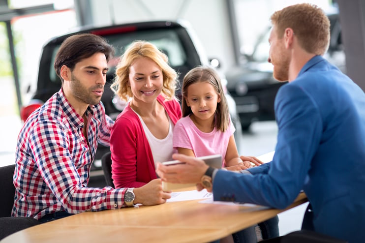 family buying car at auto dealership