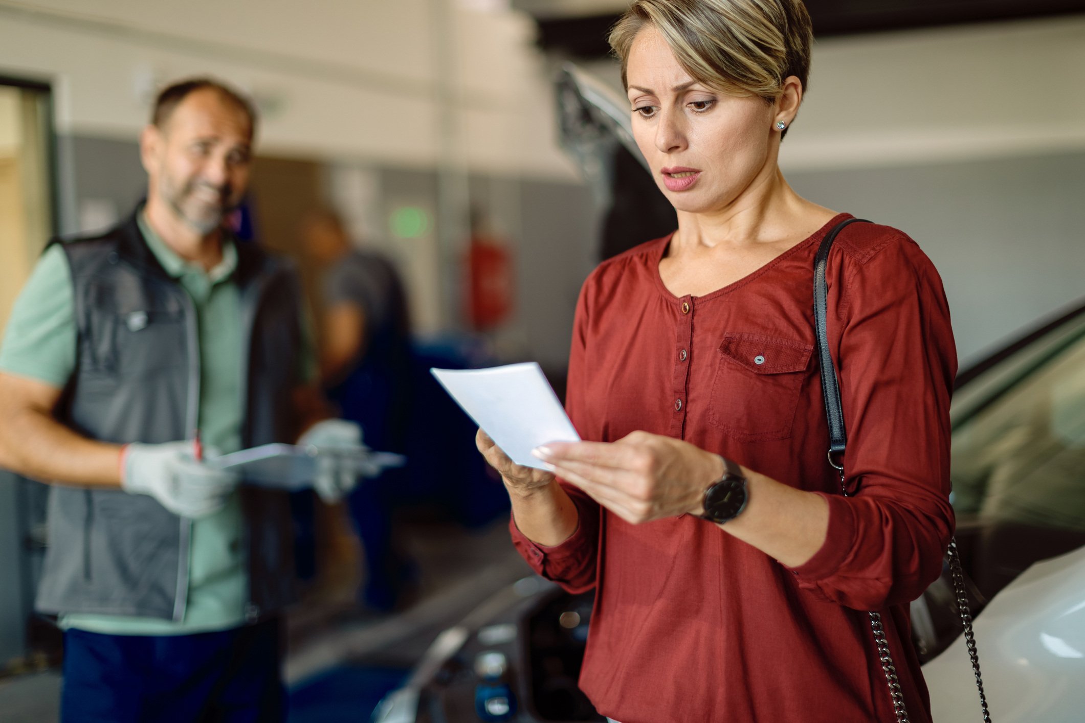 a surprised customer receiving the bill at a an auto repair shop 