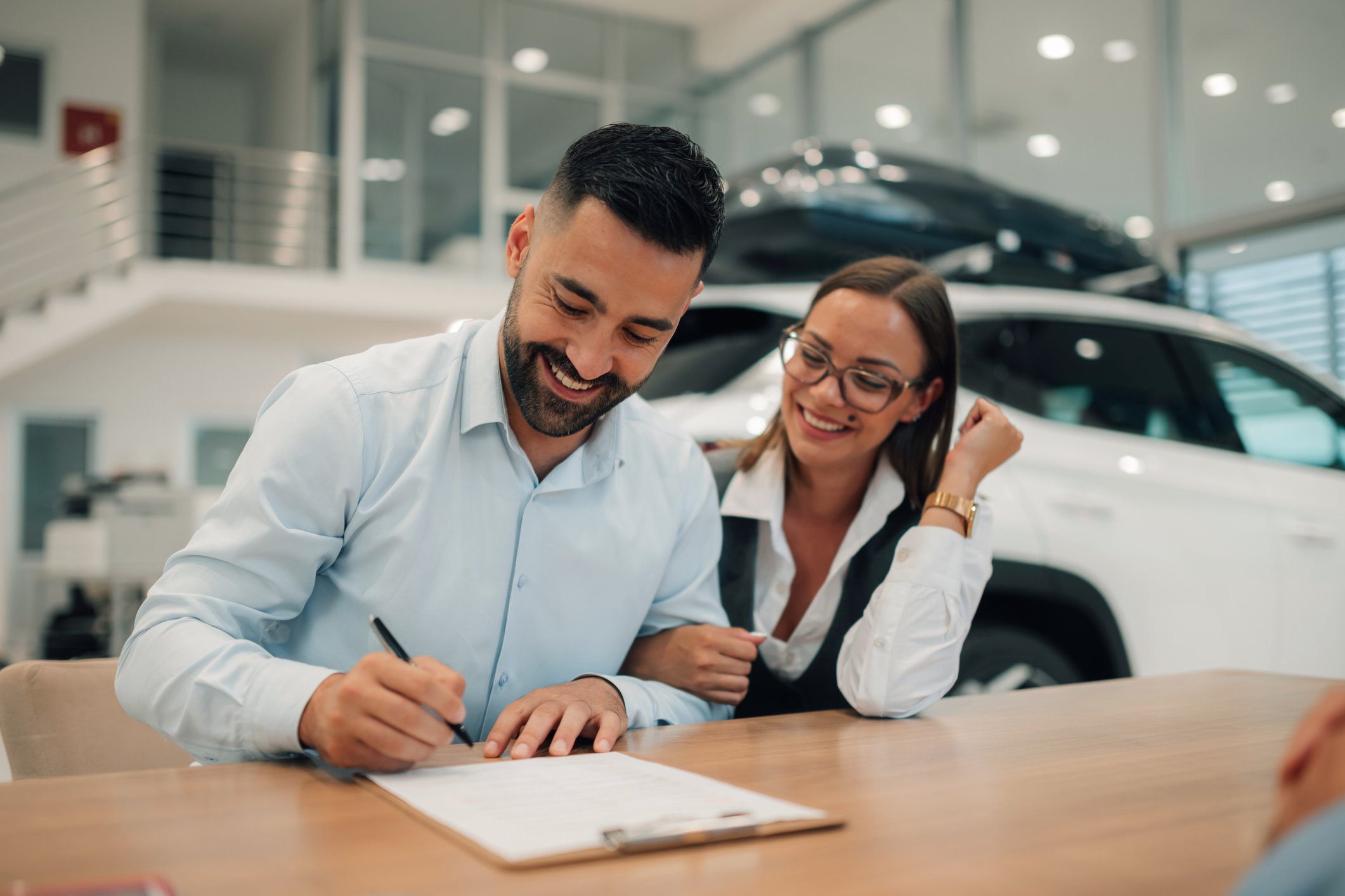 A couple signing for a new car thanks to CrossChecks Multiple Check service