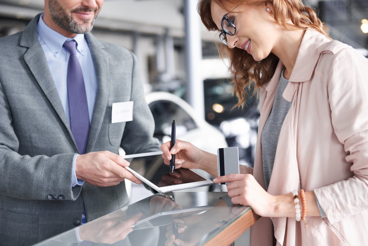 Auto salesman completes a deal with a tablet.
