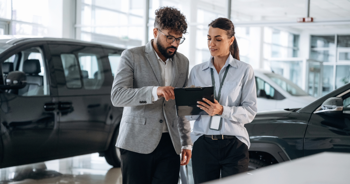 Dealership employees reviewing operational information on a tablet inside an automotive showroom
