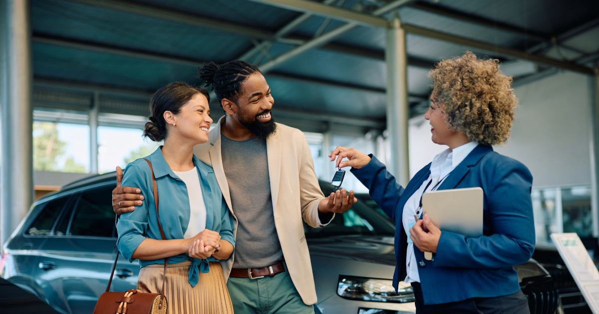 New car buyers being handed car key from dealership employee.