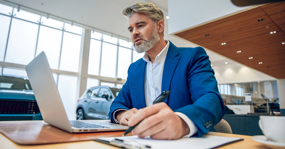 Controller at dealership reviewing expenses on laptop.