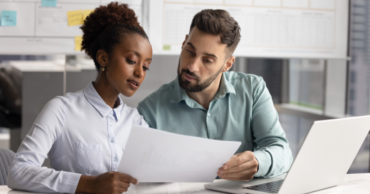 Two employees, man and woman, looking over documents to review.